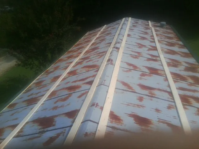 Rusted metal roof panels with new wood purlins before replacement — Storm Damage Roof Repair in Villisca by Roofing Brothers