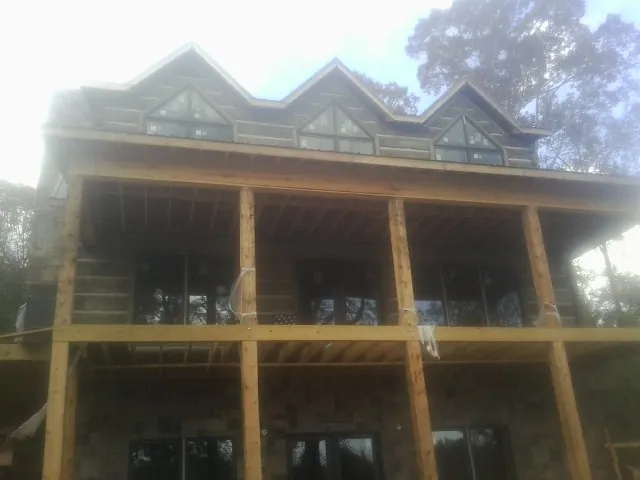 Dormers and porch framing on a large log home under construction — Roof Coating work by our crew in Villisca