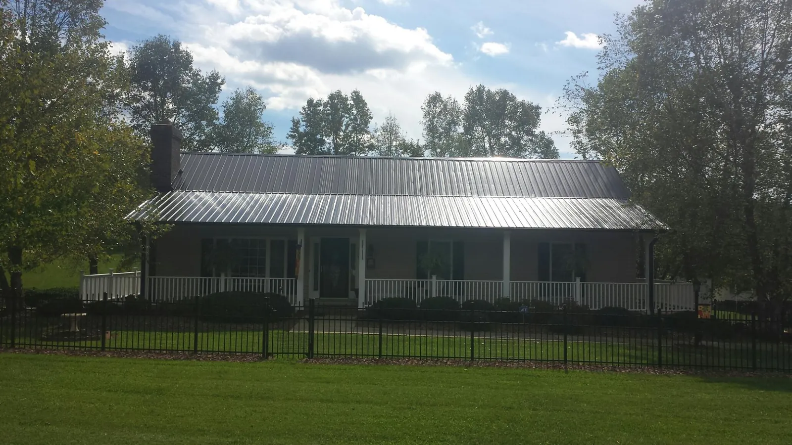 Gray metal roof on a brick ranch with a full width front porch — Gutter Guard Installation work by our crew in Villisca