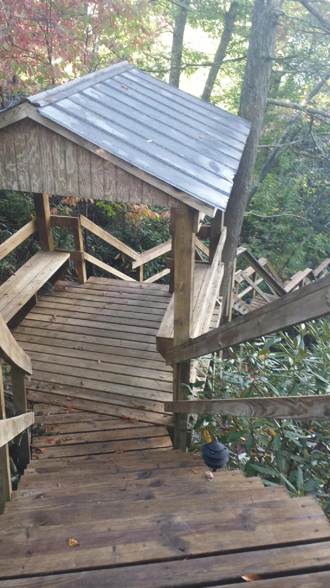 Metal roofed shelter over wooden steps on a wooded walkway — Skylight Repair & Installation work by our crew in Villisca