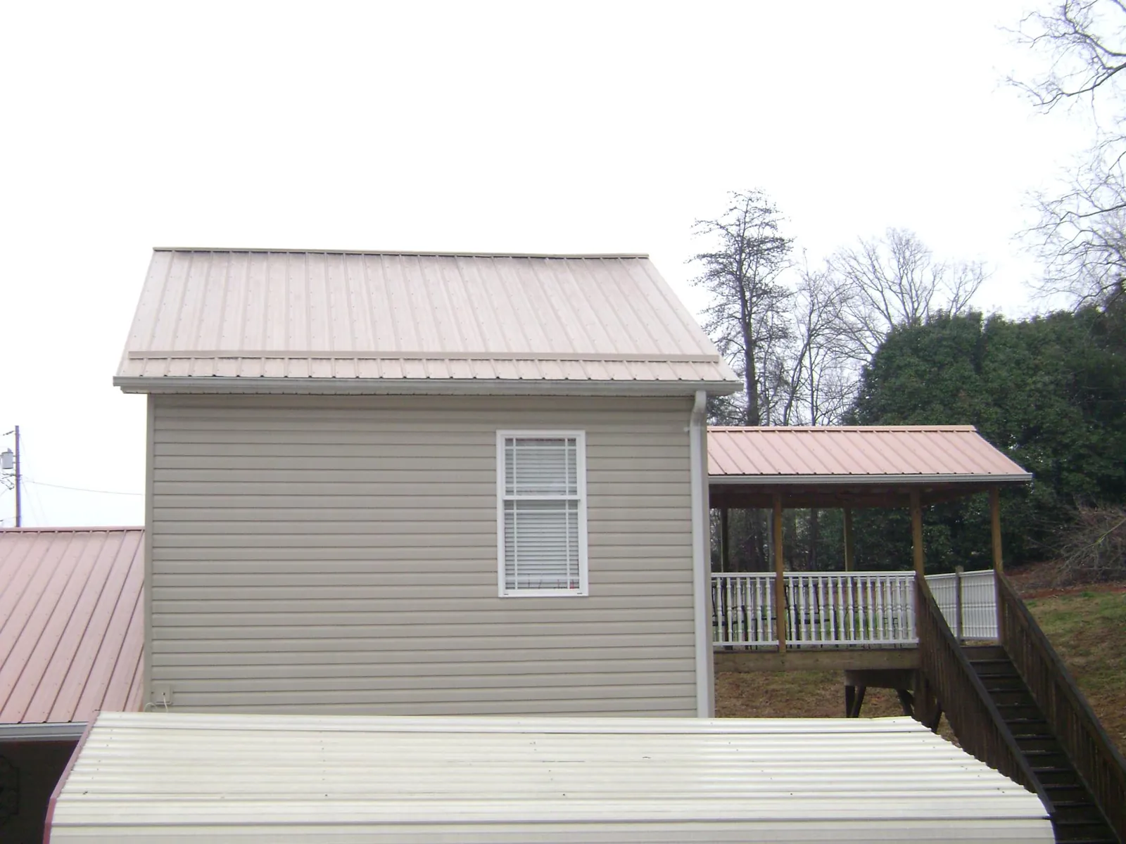 Tan metal roofs on a two story addition and attached porch, from a Roof Replacement job in Villisca