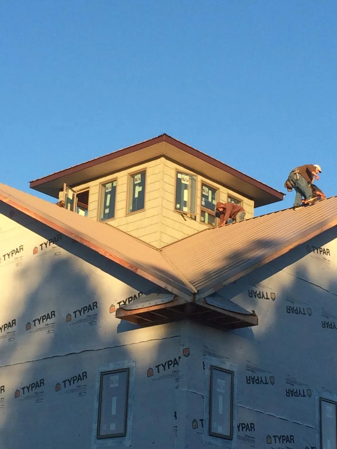 Roofers working around a rooftop cupola on a new metal roof at sunset — Roof Waterproofing in Villisca by Roofing Brothers